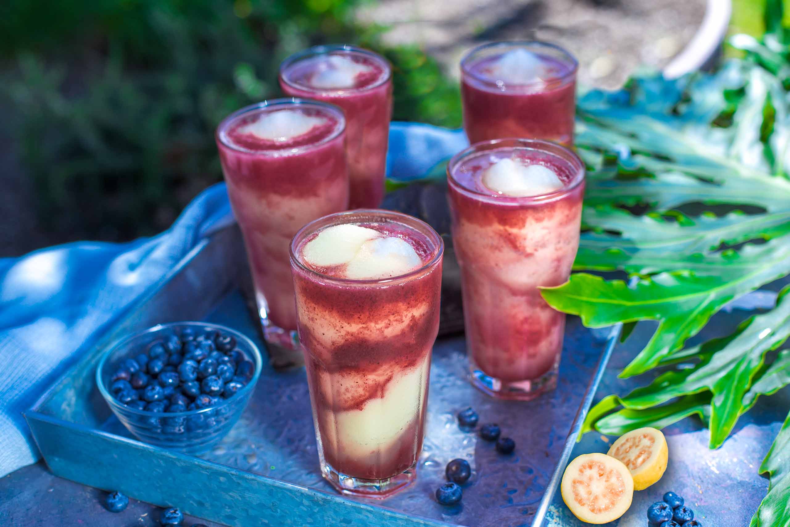 Five glasses filled with our Bacardi Blueberry Guava Swirl margaritas. Shown on our garden patio.